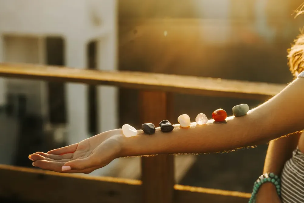 Cristais coloridos alinhados sobre o braço, na luz do fim de tarde