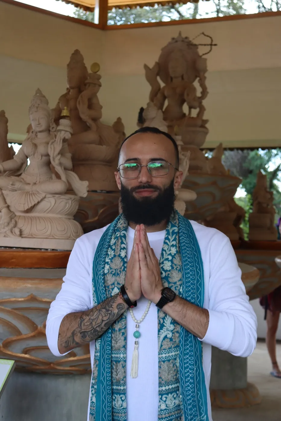 Mestre Eduardo Rocha em namastê diante de estátuas sagradas